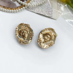 Detail of vintage gold-plated metal relief earrings with female portrait and pearls