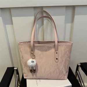 Pink minimalist tote bag with wrinkled texture and plush toy charm on white book