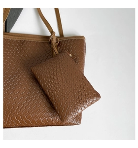 Detailed macro view of caramel woven texture on large tote bag with mini coin purse accessory