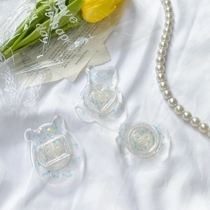 Close-up of clear resin phone grips with blue heart sequins and white 3D ribbon details