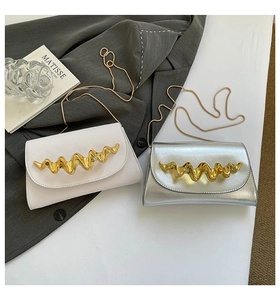 Detail of white and silver acrylic wavy metal bags with elegant gold chain straps