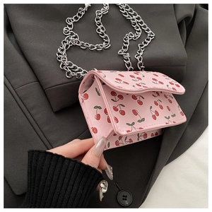Detail of mini pink crossbody bag with red cherry print and chunky silver chain link