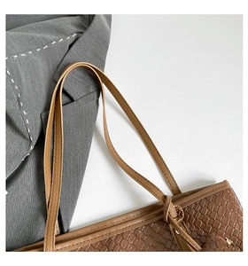 Close-up of brown woven texture tote bag with shoulder strap and mini pouch charm