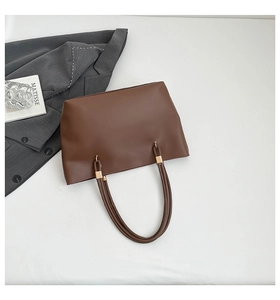 Close-up of a minimalist dark brown tote bag with premium metal hardware and smooth finish