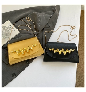 Detail of elegant gold and black leather crossbody bags with wavy metal hardware and chains