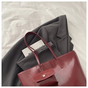 Deep burgundy glossy tote bag with matching coin purse on a minimalist grey blazer background