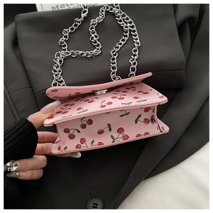 Detailed macro view of pink cherry print bag with silver chain strap and magnetic closure