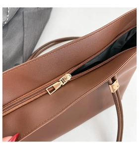Close-up of golden metal zipper and smooth brown matte leather on tote bag