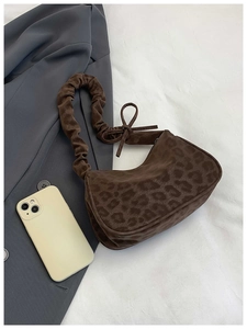 Détail du sac léopard avec bandoulière froncée et nœud sur fond de tissu blanc