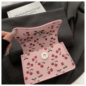 Detail of pink cherry print mini bag with magnetic silver buckle and faux leather lining