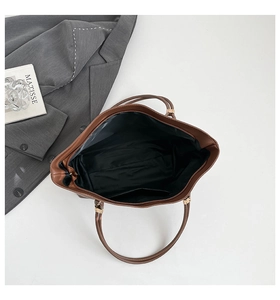 Overhead detail of large brown tote bag showing spacious black interior and inner pocket
