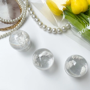 Detailed view of three transparent resin globes with white cloud-like swirls on a desk