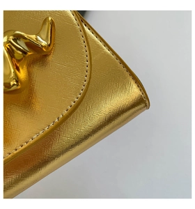 Gros plan d'un sac boîte doré avec cuir texturé et boucle métallique au design moderne