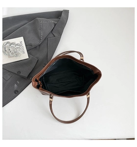 Top view of large brown leather tote bag interior with black lining and shoulder strap