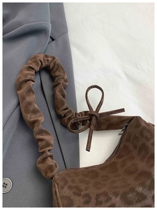 Détail du sac léopard avec bandoulière froncée et décoration de nœud en ruban élégant