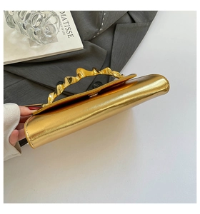 Détail de la pochette boîte dorée avec poignée ondulée en métal et texture grainée