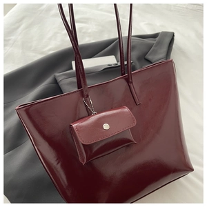 Detail of burgundy glossy leather tote bag with a matching small coin purse accessory