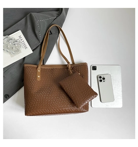 Detail of dark brown woven tote bag set with gold rivets and matching clutch