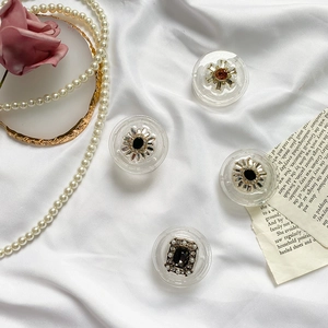 Detailed view of vintage rhinestones and pearls phone grip accessories on white silk fabric