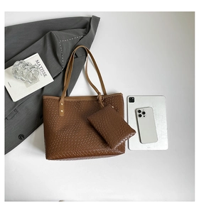 Detailed close-up of brown woven tote bag set with matching zipper pouch and gold rivets