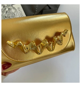 Détail du sac boîte doré avec texture croisée et boucle métallique à effet ondulé liquide