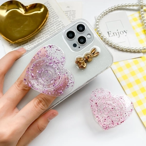 Close-up of glittery heart phone socket and rabbit charm on a clear sparkling case