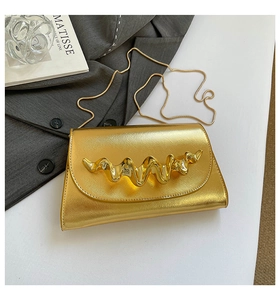 Détail du sac boîte doré avec texture croisée et ornement métallique vague 3D avec chaîne