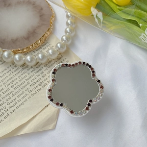 Détail macro du support de téléphone en forme de fleur avec miroir et strass rouges