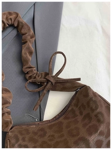Détail du sac à bandoulière en daim léopard avec anse froncée et nœud décoratif