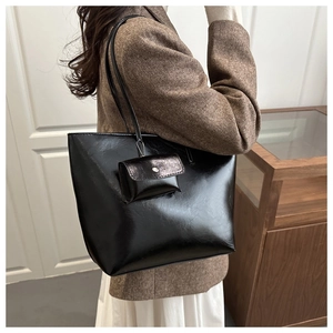 Detail of classic black tote bag with matching pouch on model in a modern office setting