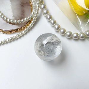 Macro detail of transparent cloud planet phone grip with silver glitter and resin finish