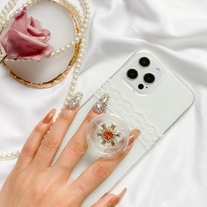 Detail of luxury rhinestone phone grip with orange stone and pearls on silk