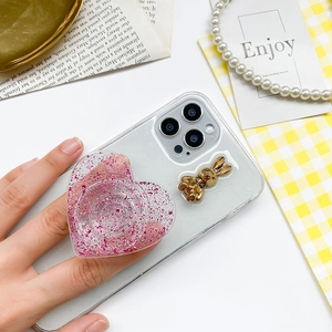 Pink glitter heart pop socket with gold bunny on transparent phone case used by hand