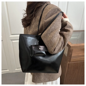 Detail of glossy black leather tote bag with matching small coin pouch and slim shoulder straps