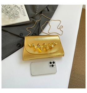 Détail du sac bandoulière doré texturé avec chaîne et téléphone pour échelle de taille