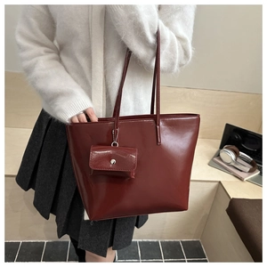 Deep burgundy large tote bag with matching small pouch worn on white sweater