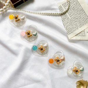 Detailed view of heart-shaped phone grips with 3D bears on white satin background