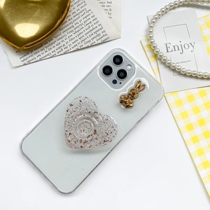 Detail of transparent phone case with heart glitter socket and small golden bunny decor