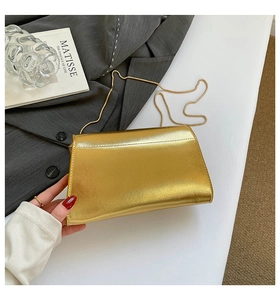 Détail d'un sac boîte doré avec finition en métal brossé et fine bandoulière chaîne