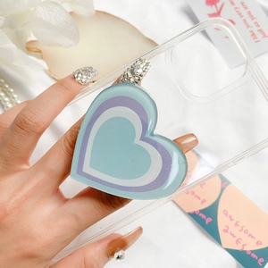 Detail view of heart-shaped phone grip with rhinestones on a clear protective case