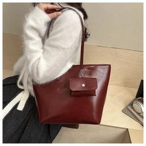 Detail of burgundy glossy leather tote bag with matching coin purse on a desk