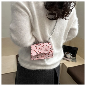 Detail of pink cherry print crescent bag with silver chain strap and wavy flap edge