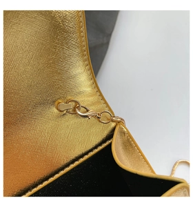 Détail du sac boîte doré avec fermoir mousqueton et texture à motif croisé
