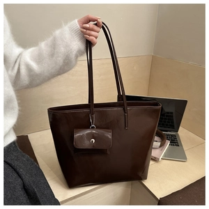 Detail of dark brown tote bag with glossy faux leather and matching small pouch
