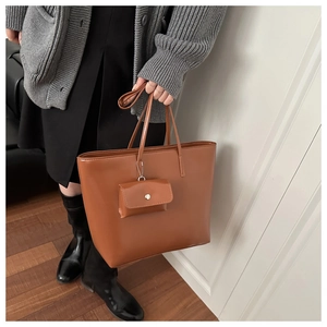 Detail of a brown leather tote bag featuring a matching small coin purse charm pendant
