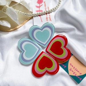 Macro detail of acrylic heart phone grips in red and blue tones on silk fabric