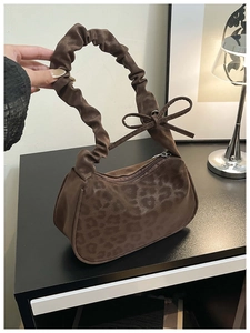 Détail du sac léopard avec poignée à volants et décoration de nœud sur le côté du sac