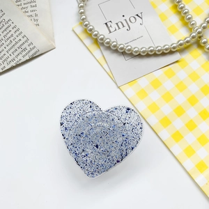 Detail of blue glitter heart phone grip holder on yellow aesthetic background