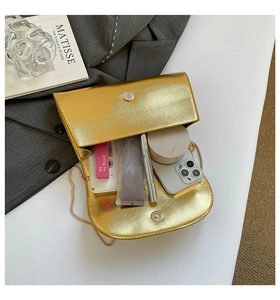 Vue détaillée de l'intérieur d'un sac boîte doré contenant téléphone et maquillage