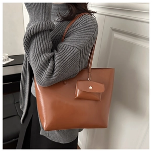 Detail of caramel brown soft leather tote bag with small matching pouch on casual sweater
